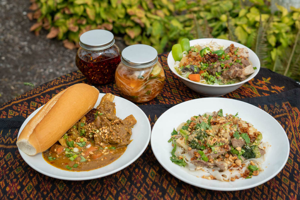 A spread of three authentic Cambodian dishes and two jars of chili oil paste and pickled vegetables