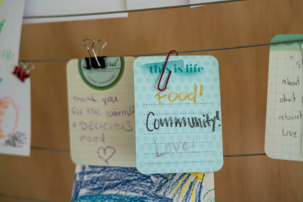 Cards hang on a line at Spice Bridge. One bears the message "Food! Community! Love!"